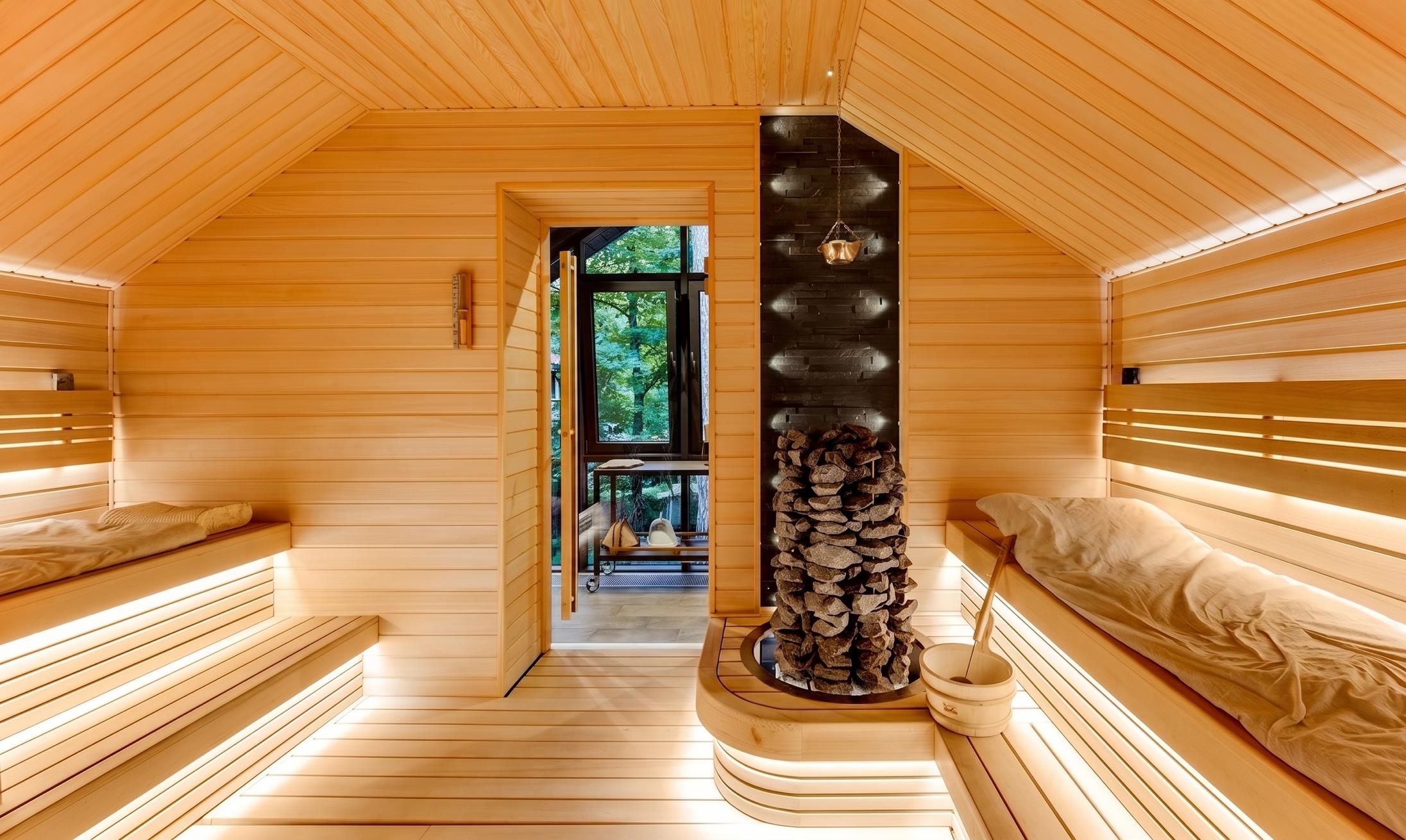 Spa House interior — Finnish sauna with stacked timber and stove.